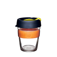 Reusable glass coffee cup with orange silicone sleeve and dark lid, 12oz medium