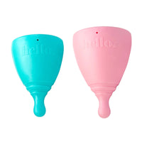 Teal and blush menstrual cups side by side, each with short stem and 'hello'